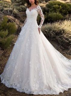 a woman in a wedding dress standing on a hill