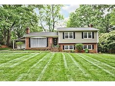 a house with lawn mowed in front of it and trees around the back yard