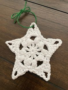 a white crocheted star ornament hanging from a string on a wooden table