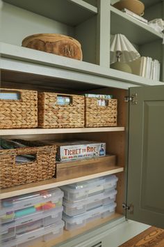 an organized pantry with wicker baskets and plastic bins on the bottom shelving