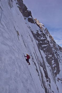 a man climbing up the side of a snow covered mountain