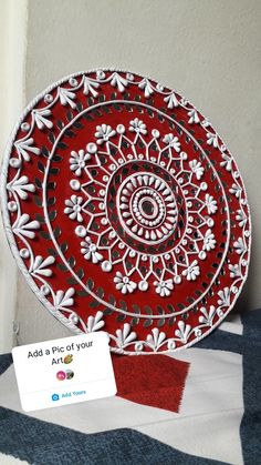 a red and white plate sitting on top of a bed next to a postcard