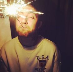 a man with his eyes closed while holding a sparkler in front of his face