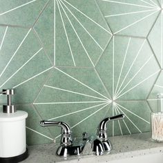 two faucets and soap dispenser in front of green geometric tile