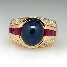 This exquisite ring is centered with an oval, sapphire cabochon in a partial bezel setting. The shoulders are each channel set with four (4) square mixed cut rubies. The top of the ring is bead set with a total of forty-six (46) round brilliant cut diamonds. The ring measures 13.7mm at the top, rises 11.2mm above the finger, tapering to 5.5mm wide and 1.3mm thick at the base of the shank. This ring is currently a size 7. Formal Oval Cabochon Sapphire Ring, Luxury Multi-stone Cabochons For Formal Occasions, Luxury Oval Cabochon Ruby Ring, Luxury Sapphire Cabochon Ring, Luxury Sapphire Cabochon Ring For Anniversary, Elegant Sapphire Cabochon Rings, Classic Cabochon Sapphire Ring For Formal Occasions, Formal Polished Finish Oval Cabochon Sapphire Ring, Luxury Ruby Ring With Oval Cabochon