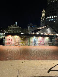 the word boston is written in multicolored letters on a brick walkway at night