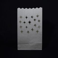 a white paper bag with black stars on the front and bottom, against a dark background