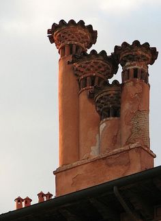 the top of an old building with three chimneys and two birds on it's roof