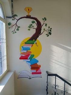 a room with a tree painted on the wall next to a book shelf filled with books