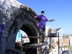 a man standing in front of a stone oven