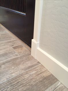 the corner of a room with wood flooring and a door handle on it's side