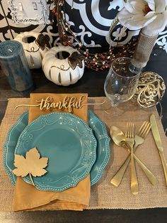 a place setting with blue plates and gold napkins, pumpkins and white flowers