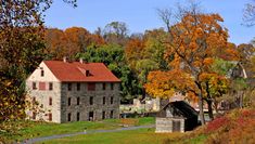 an old stone house surrounded by trees in the fall