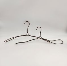 two wire hangers are shown on a white background, one is black and the other is brown