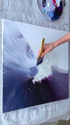 a person using a brush to paint on a canvas