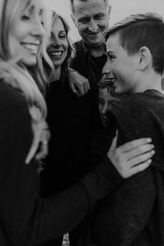 a group of people standing next to each other with their arms around one another and smiling