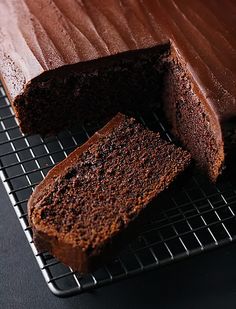 there is a chocolate cake that has been sliced on the cooling rack with one slice taken out