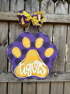 a purple and yellow dog paw shaped door hanger with the word tigers on it