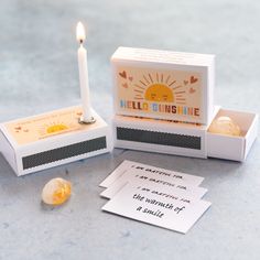 an open matchbox with a single candle on it next to two cards that say hello sunshine