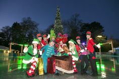 a group of people standing next to each other in front of a lit up christmas tree