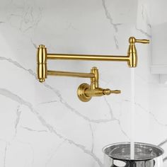 a gold faucet on the wall in a bathroom with white marble walls and flooring