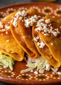 three tortillas on a plate with lettuce and feta cheese toppings