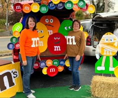 two women standing in front of a truck decorated with m's and m's