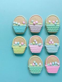 six decorated cookies in the shape of baskets on a blue background with pastel colors