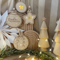 christmas ornaments are on display in front of a striped curtain and tree with lights around them