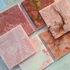 several different types of soaps on a counter top, including pink and white marble