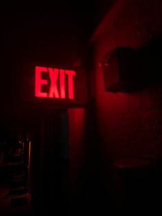 an exit sign lit up in the dark with red light coming from it's side