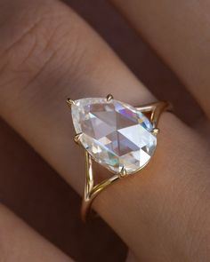 a woman's hand with a ring on it that has an oval shaped diamond in the center