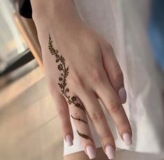 a woman's hand with a henna tattoo on her left wrist and fingers