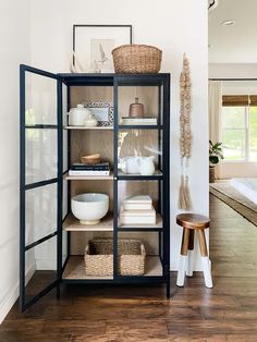 an open bookcase in the corner of a room with wooden floors and white walls