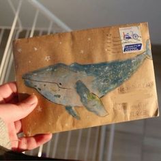 a person holding up a piece of paper with a whale on it's side