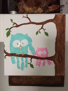 two owls are sitting on a tree branch and one is painted with handprints