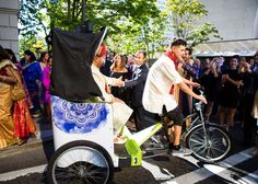 a man riding on the back of a bike next to a woman in a white dress