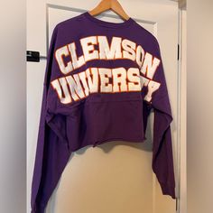 a purple clemson university sweatshirt hanging on a door