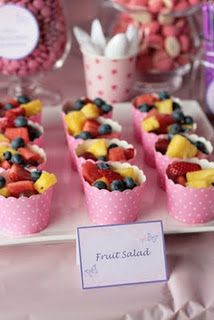 small cups filled with fruit salad on top of a white plate next to other desserts