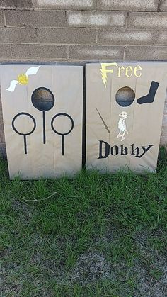 two cardboard boxes sitting in the grass near a brick wall