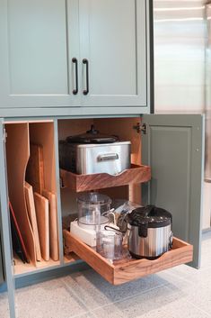 an open cabinet with pots and pans in it