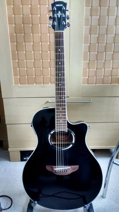 a black guitar sitting on top of a chair