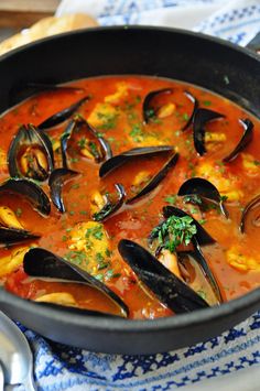 a pan filled with mussels and sauce on top of a table