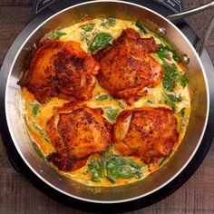 a pan filled with chicken and cheese on top of a wooden table