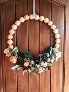 a wooden wreath with flowers and greenery hangs on the front door