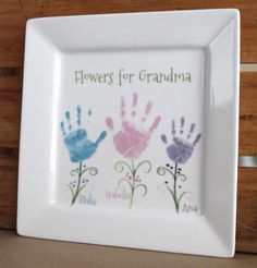 there is a white plate with handprints on it that says flowers for grandma