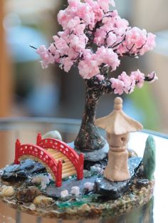 a bonsai tree with pink flowers and a bridge