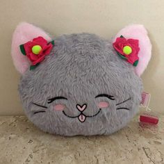 a gray cat purse with pink ears and flowers on it's head sitting on a counter