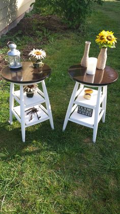 two small tables sitting in the grass with sunflowers