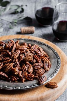 a plate full of pecans sitting on top of a table next to two glasses of wine